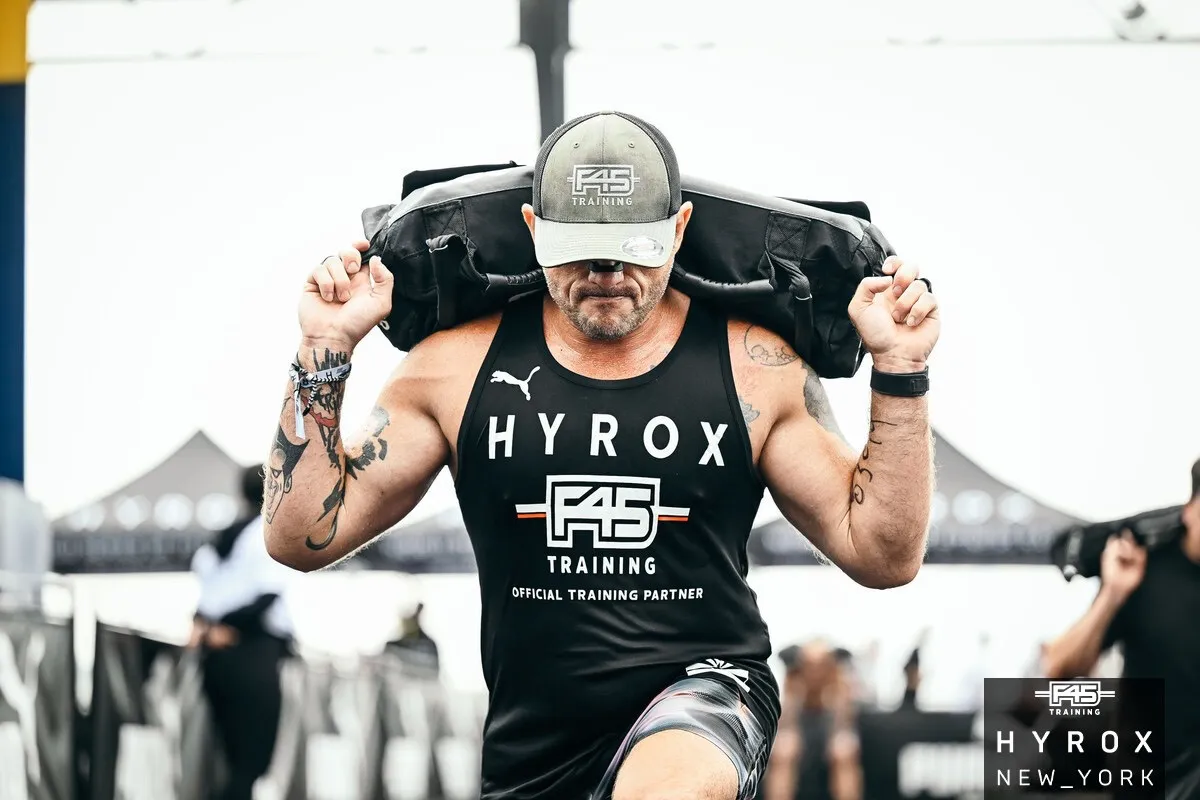 Spencer Hornock carrying a sandbag during a HYROX race